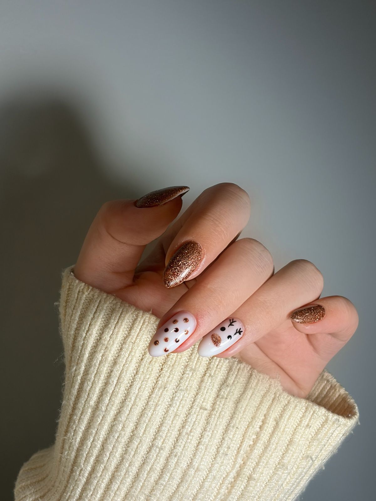 Amandelnagels met koperkleurige glitter en witte nagels met zwarte stippen