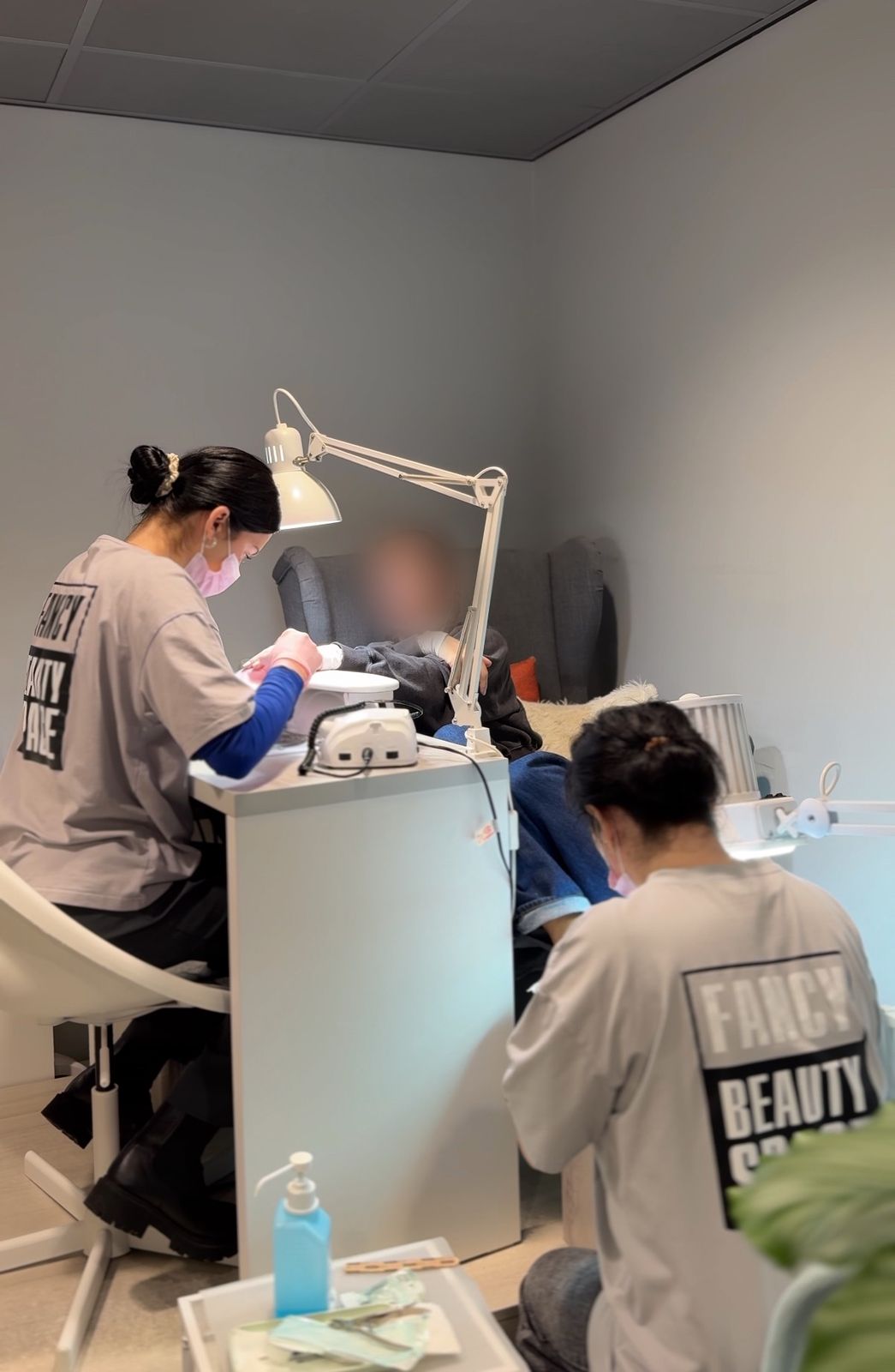 Twee specialisten van Fancy Beauty Space werken tegelijk aan de handen en voeten van een klant