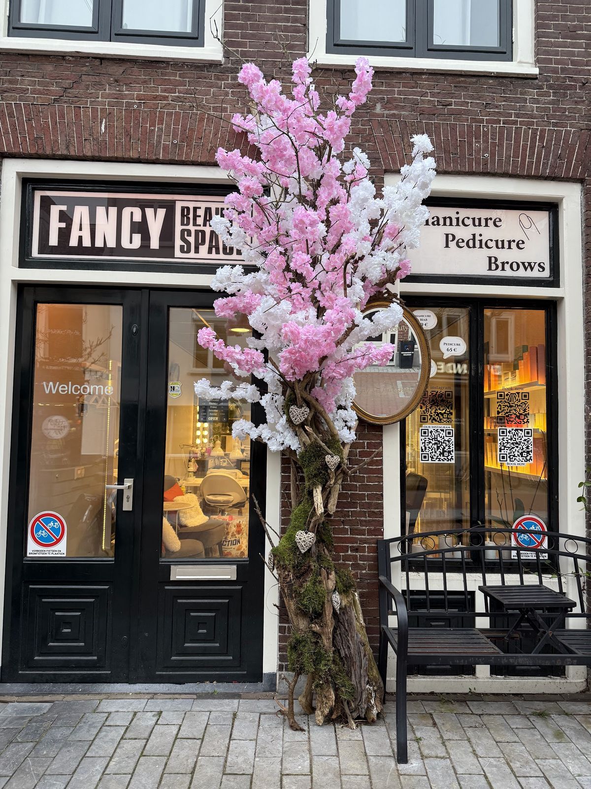 Gevel van Fancy Beauty Space aan de Rijnstraat met een roze en witte bloesemboom bij de deur